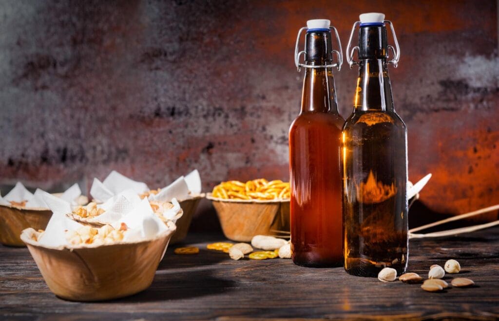 Bottles of beer with bowls of snacks on a rustic table