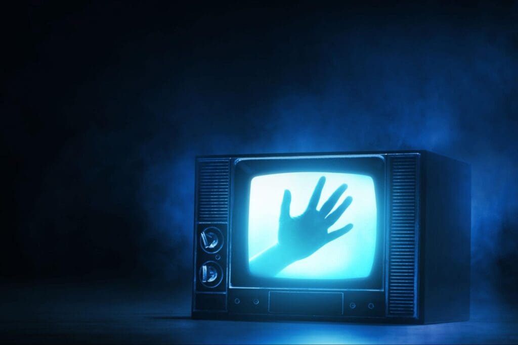 Creepy scene with a hand pressing against the screen of a vintage television