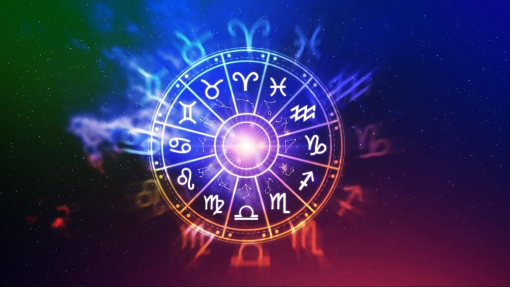 Colorful illustration of a zodiac wheel with astrological symbols glowing against a dark cosmic background with nebulous clouds and starlight.