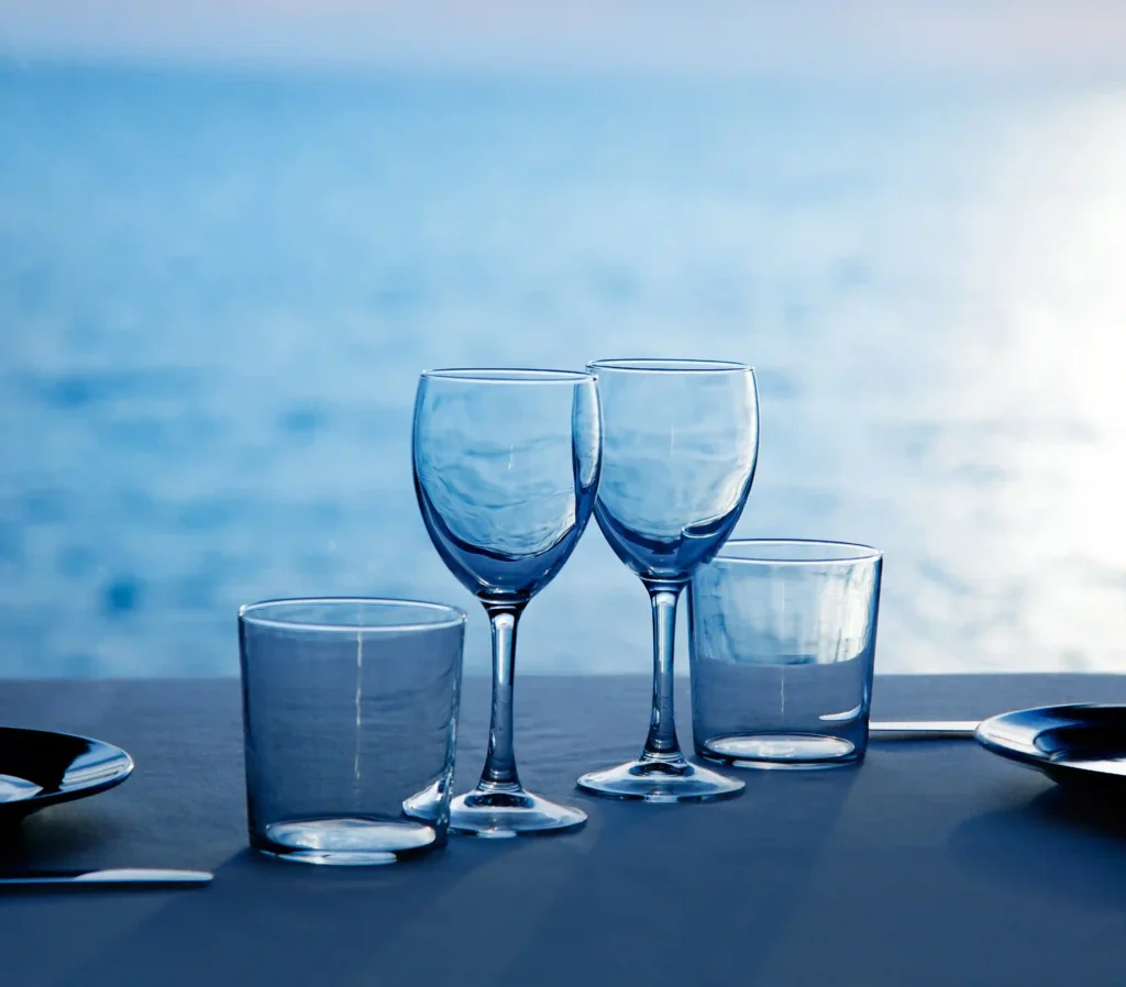 Empty wine glasses set on a table by the sea, symbolizing an elegant dinner cruise.