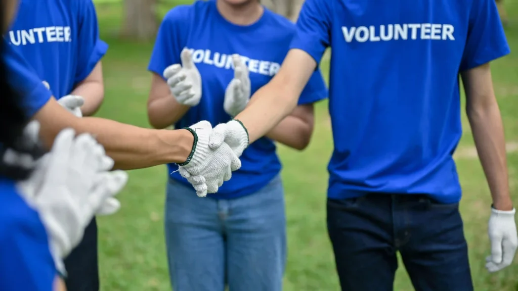 Volunteers in blue shirts shaking hands and working together during a charity event.