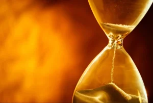 Close-up of an hourglass with golden sand flowing down.