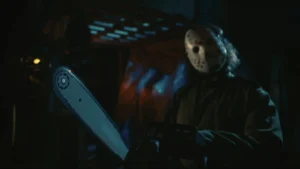 Horror movie-style masked figure holding a chainsaw in a dark setting.