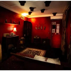 Vintage-themed room with red walls, magical props, and ambient lighting in Kellar's Magic Emporium escape room.