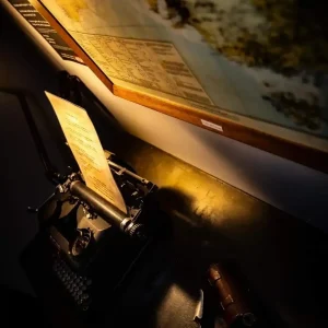 Vintage typewriter with a mysterious note and map on the wall, part of the immersive setting in the Mine Escape room at Escape Room Melbourne.